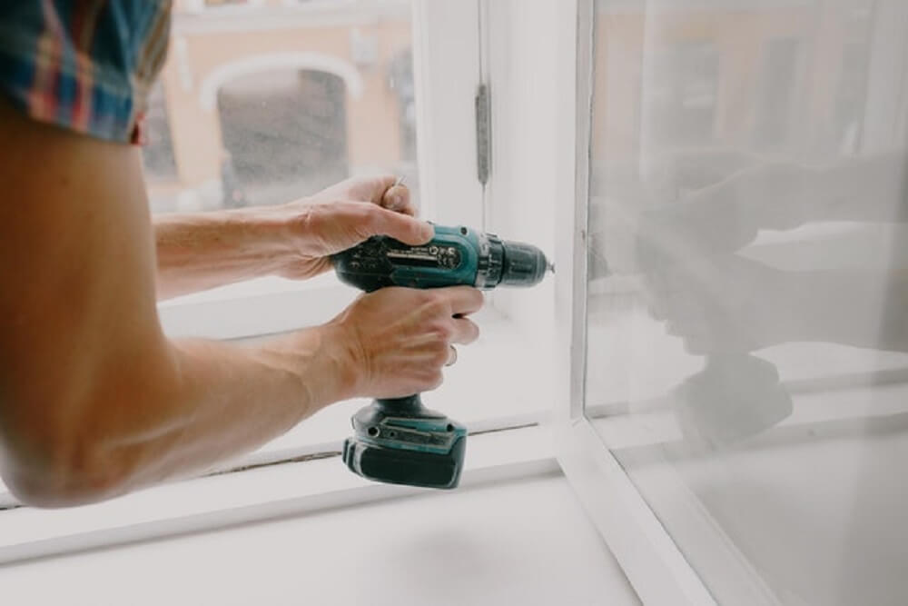 A man screwing a window frame.