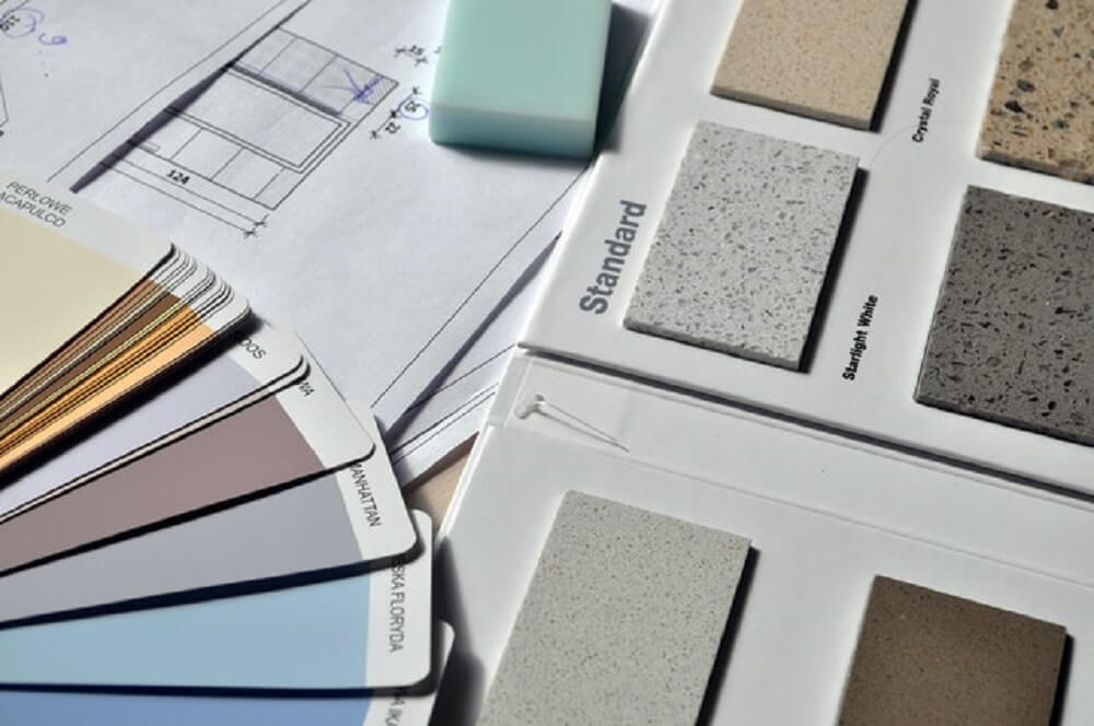 A paint color book next to house remodel plans.