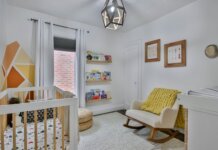 DIY Nursery Decor Tips A nursery painted white with a chair, bookshelf and two paintings on the wall.